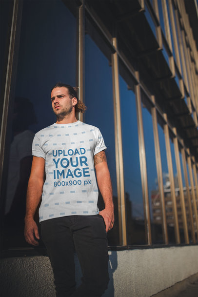 Mockup of a Man Wearing a Sublimated Tshirt Against a Building's Mirrors
