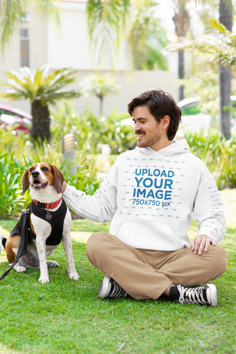 Mockup of a Man in a Gildan Hoodie with Customizable Sleeves Sitting Next to His Pet