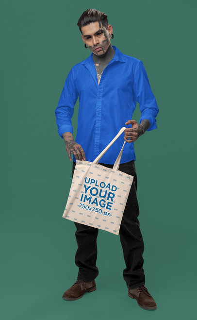 Mockup of a Tattooed and Serious Man Carrying a Sublimated Tote Bag in a Studio m31669