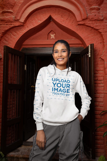 Gildan Hoodie Mockup of a Smiling Woman Posing in Front of a Door