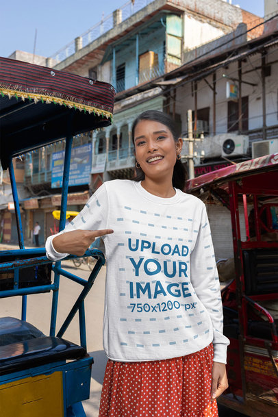 Mockup of a Smiling Woman Pointing at Her Rounded-Neck Sweatshirt on the Street