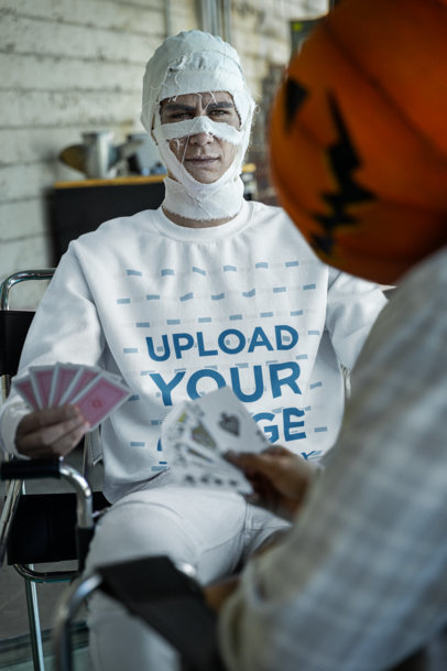 Halloween-Themed Gildan Sweatshirt Mockup of a Man Playing Cards in a Mummy Costume  m35493