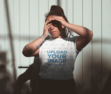 Mockup of a Tattooed Woman with Locs Wearing a Sublimated T-Shirt Blocking the Sun