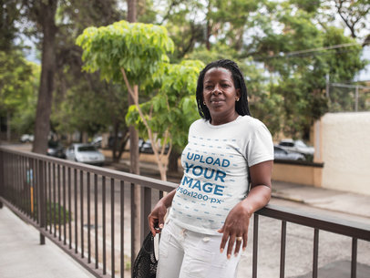 T-Shirt Mockup of a Serious Elderly Woman Leaning Against an Iron Fence a21409