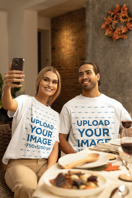 Stanley Stella T-Shirt Mockup of a Woman and a Man Posing Happily for a Selfie in a Thanksgiving Dinner