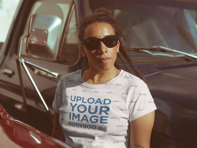 Mockup of a Woman Wearing a Sublimated T-Shirt Leaning Against a Truck