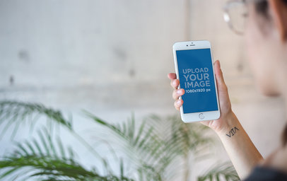 Template of a Woman Using a Silver iPhone 8 Plus Near a Plant a21285