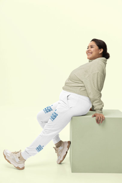 Cotton Heritage Sweatpants Mockup Featuring a Happy Woman Sitting in a Cube at a Studio