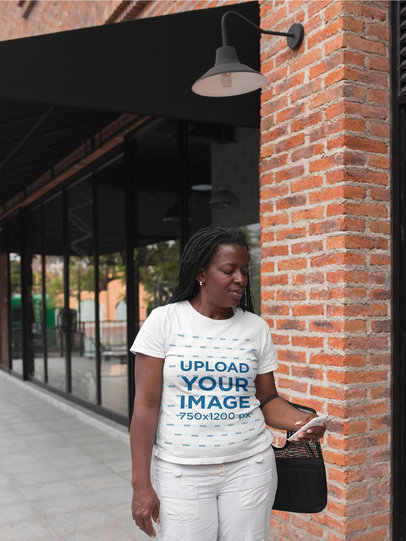 T-Shirt Mockup of a Woman Walking Down the Street Checking her Smartphone a21407