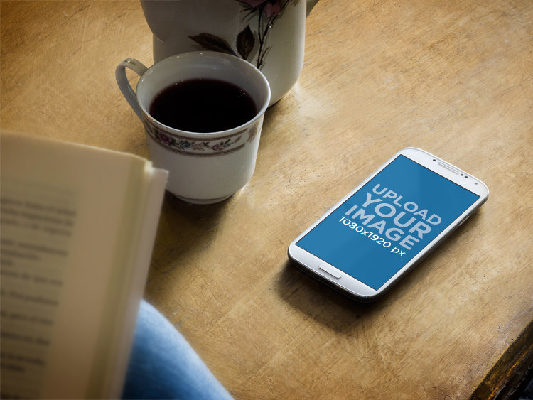 Mockup of a Samsung Galaxy Lying on a Wooden Desk With a Cup of Coffee