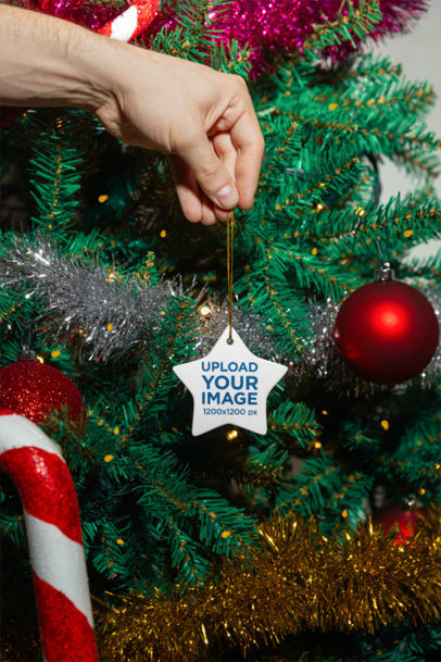 Mockup of a Person Holding a Ceramic Ornament Near a Christmas Tree