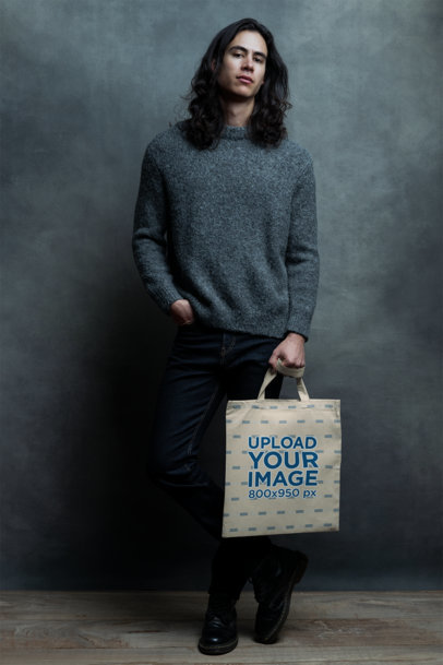 Tote Bag Mockup Featuring a Male Model with Long Hair Posing in a Studio
