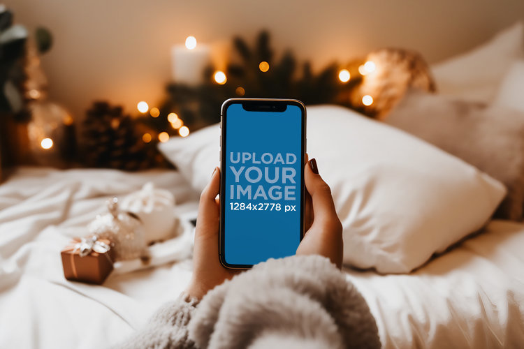 Christmas Mockup of a Woman Using Her iPhone on Her Bedroom