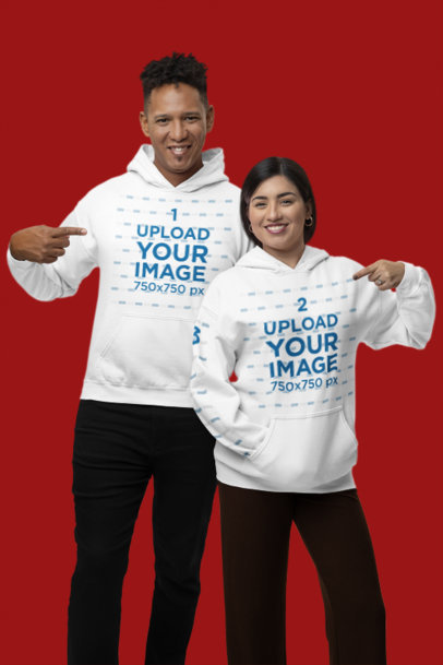 Mockup of a Happy Couple Pointing at Their New Gildan Pullover Hoodies m36321
