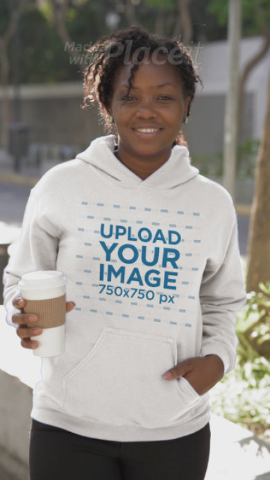 Gildan Hoodie Pullover Video Featuring a Happy Woman Posing in the Street and Drinking Coffee