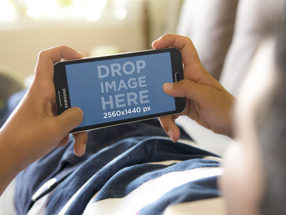 Android Mockup of Boy Laying on the Couch Playing with Samsung Galaxy