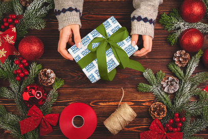 Wrapping Paper Mockup of a Woman Holding a Christmas Present and Surrounded by Holiday Decorations