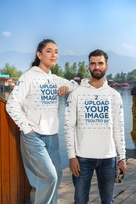 Mockup of a Man and a Woman Wearing Matching Gildan Pullover Hoodies by a Lake