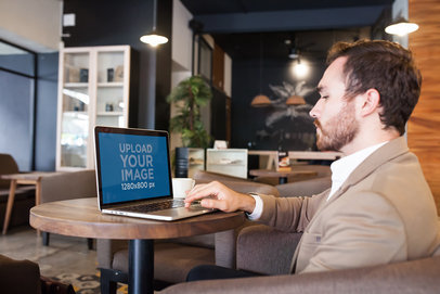 MacBook Mockup Featuring a Man Working while at a Coffee Shop