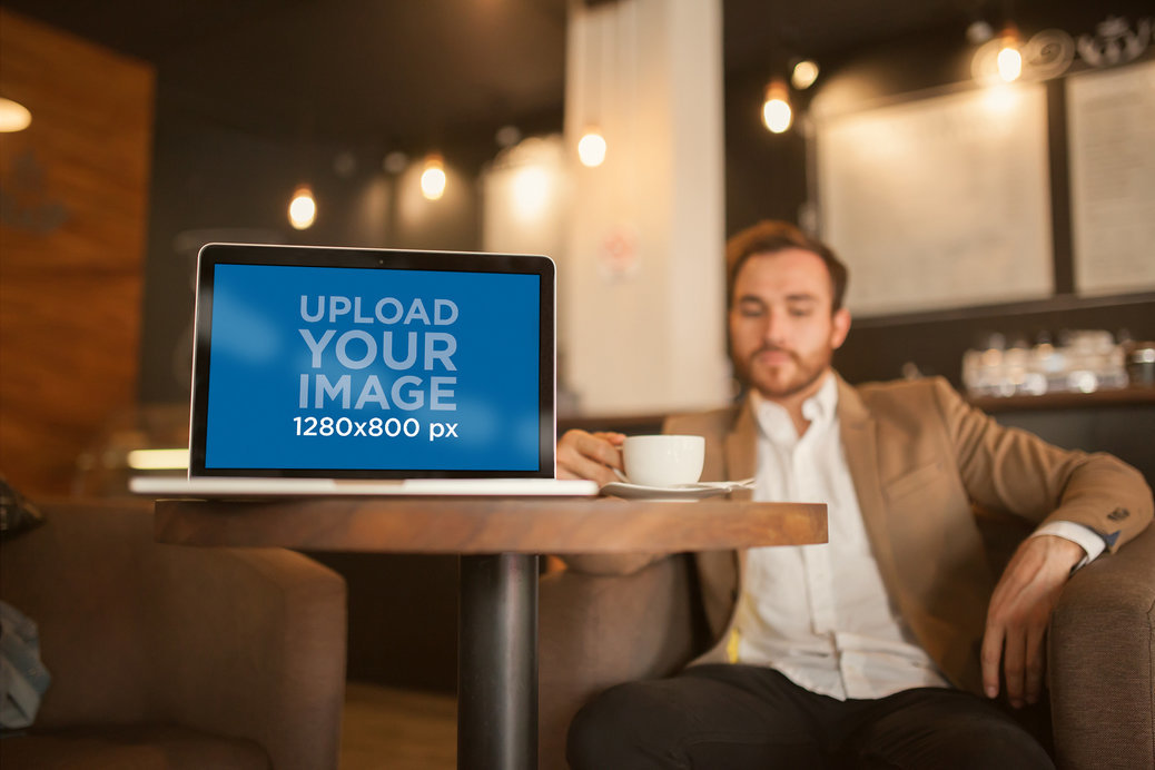 Mockup of a MacBook Standing on a Table Near a Businessman at a Cafe
