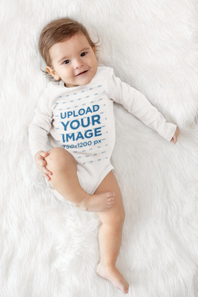Long-Sleeve Onesie Mockup of a Happy Baby Lying over a Soft Cloth