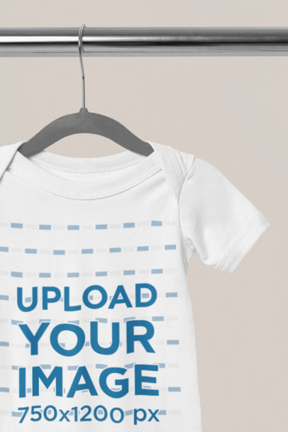 Mockup of a Bella Canvas Onesie Hanging from a Steel Bar