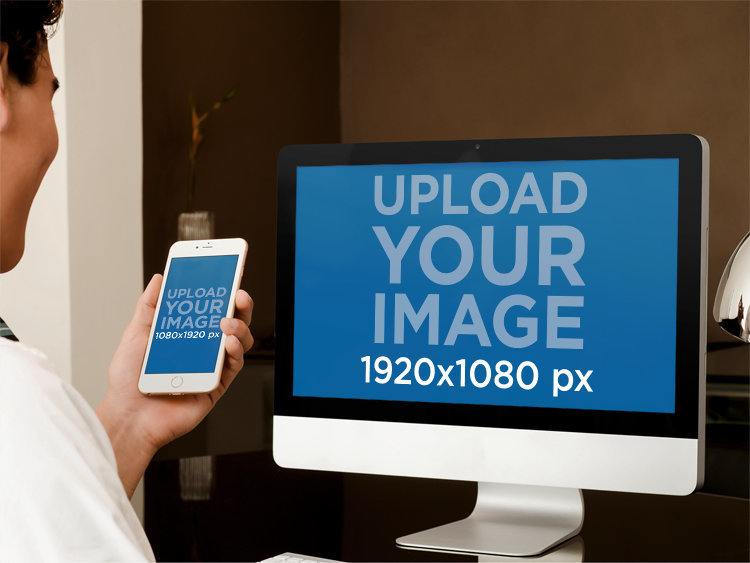 iMac Mockup Featuring a Man Checking His iPhone at an Office