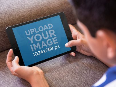 Tablet Mockup of Boy Playing With iPad Mini on the Couch
