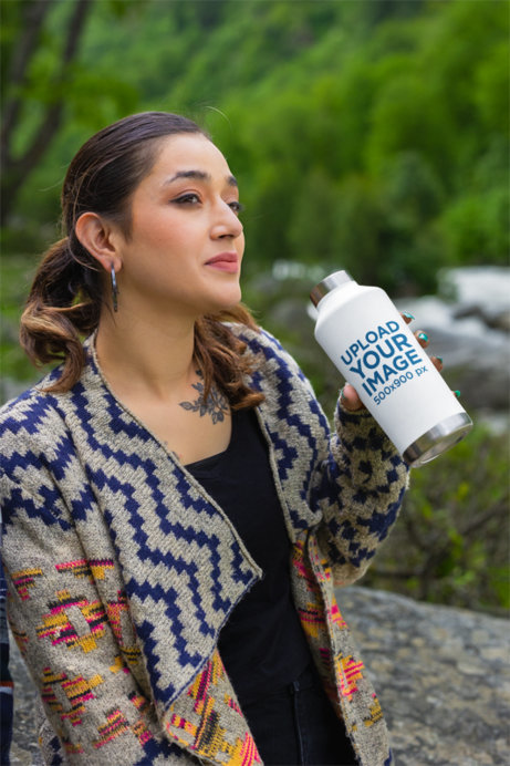 Mockup of a Tattooed Woman Holding a Travel Mug While Posing in the Mountains