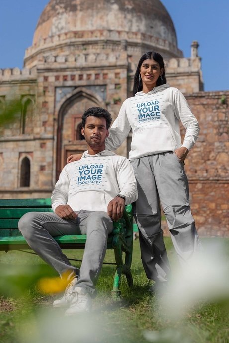 Gildan Pullover Hoodie Mockup of a Man Sitting on a Bench While Posing With a Woman