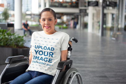Mockup of a Woman Using a Wheelchair and Wearing a T-Shirt Outside a Mall
