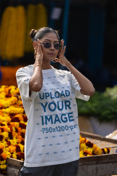 Blinkstore T-Shirt Mockup Featuring a Woman Standing in Front of a Bunch of Flowers