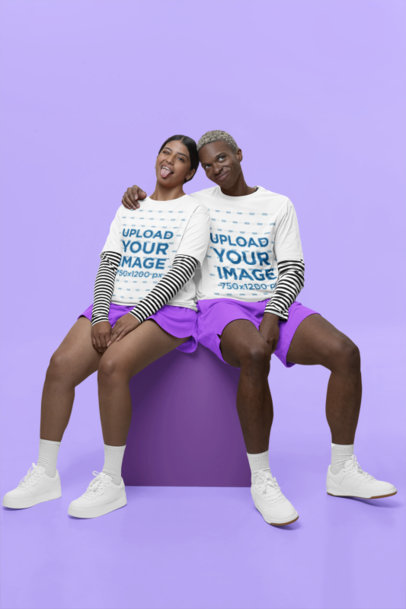 Stanley Stella T-Shirt Mockup Featuring a Happy Man and Woman Sitting on Studio Against a Colorful Backdrop