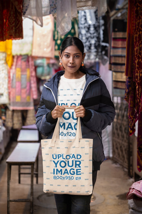 Blinkstore T-Shirt Mockup of a Woman Carrying a Tote Bag in a Street Market