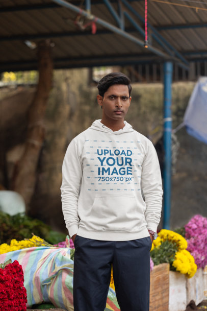 Mockup of a Serious-Looking Man Wearing a Gildan Hoodie at a Market