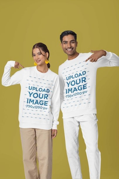Mockup of a Smiling Man and Woman Pointing at Their Matching Sweatshirts in a Studio