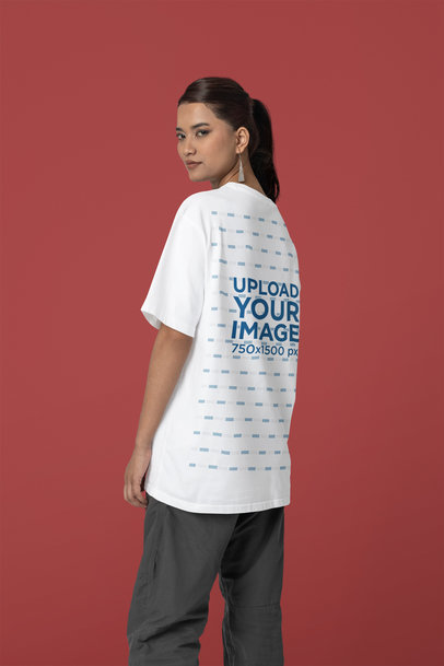 Back-View Mockup of a Woman Standing in a Studio Wearing an Oversized Blinkstore Tee