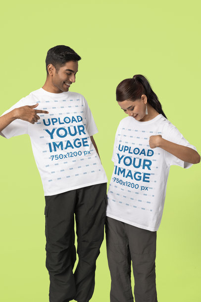 Mockup of a Man and a Woman Pointing at their Own Blinkstore T-Shirt in a Studio