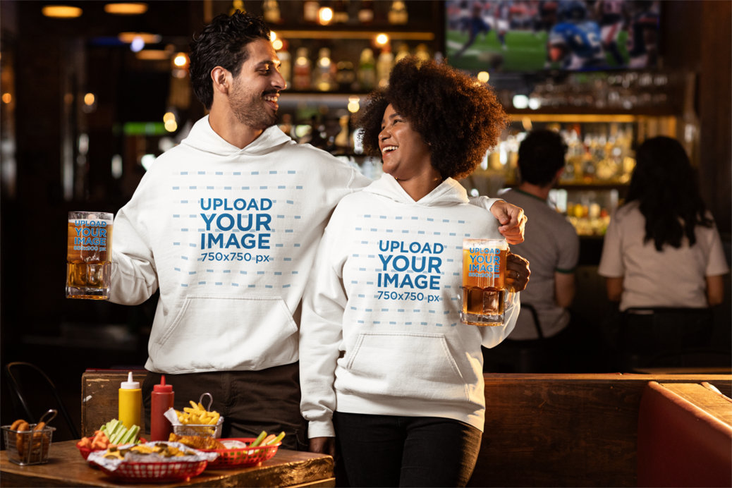 Gildan Pullover Hoodie Mockup of a Happy Man and Woman Drinking Beer in a Sports Bar