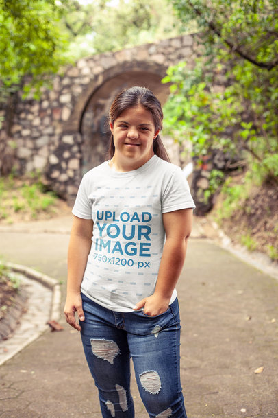 T-Shirt Mockup of a Smiling Woman Standing Near a Bridge at a Park
