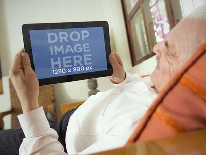 Mockup of an Elderly Man Laying On a Sofa With a Samsung Tablet