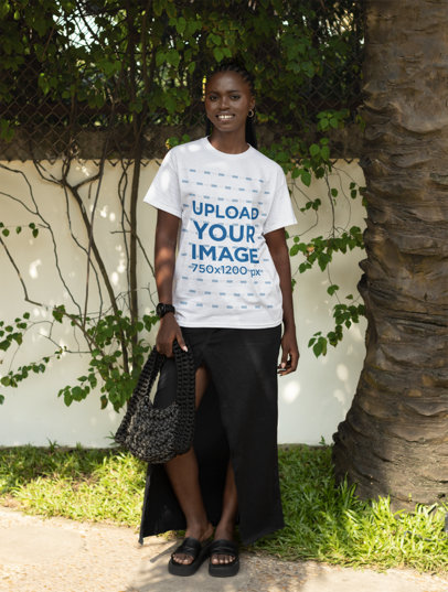 T-Shirt Mockup of a Smiling Woman Posing Near a Garden