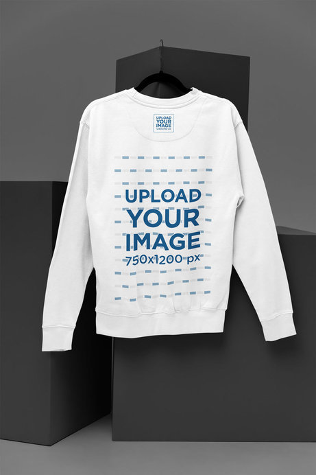 Mockup of a Sweatshirt from Cotton Heritage with a Clothing Label Hanging in a Minimalist Setting