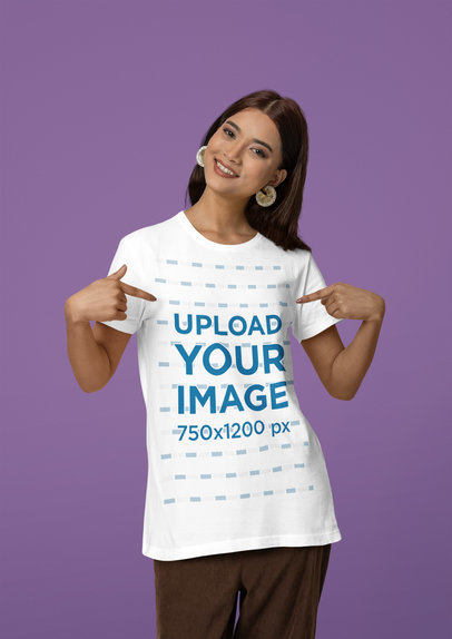 Mockup of a Happy Woman Pointing at Her Scott International T-Shirt in a Studio