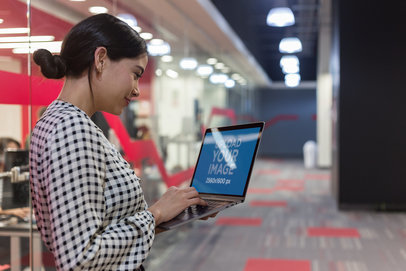 Mockup of a Happy Woman Standing and Using a MacBook