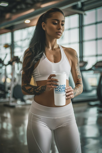 AI-Created Mockup Featuring a Tattooed Woman Holding a Tumbler in a Gym