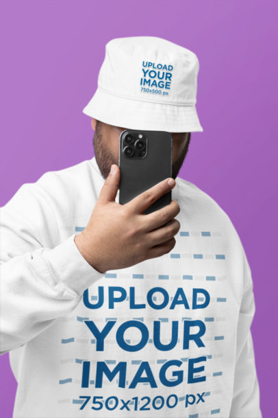 Bucket Hat and Gildan Sweatshirt Mockup of a Man Hiding His Face With a Smartphone
