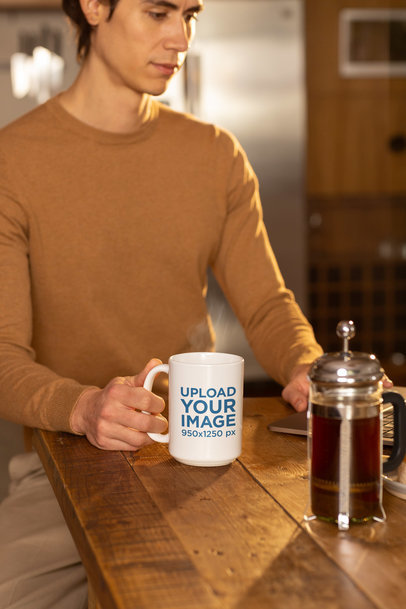 Mockup of a Serious Man Grabbing a 15 Oz Coffee Mug While Posing in a Kitchen
