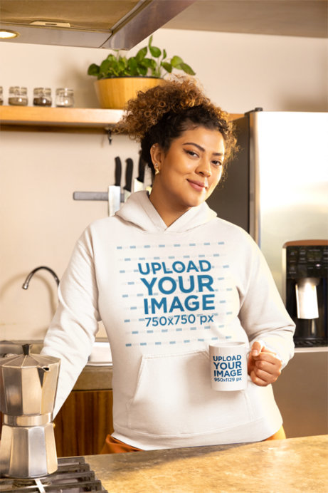 Gildan Hoodie Mockup Featuring a Smiling Woman Posing With a Coffee Mug in a Kitchen