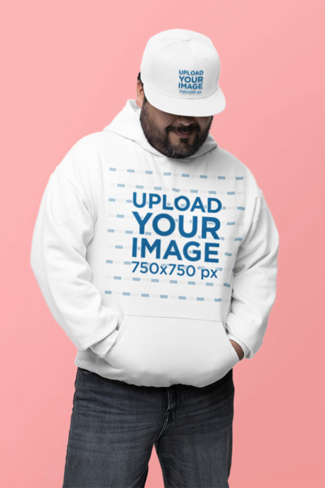 Gildan Hoodie and Snapback Hat Mockup of a Bearded Man Standing Against a Colorful Backdrop
